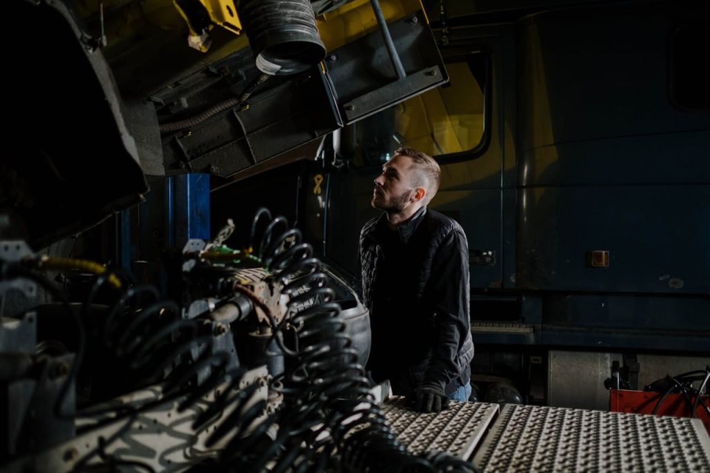 A truck mechanic carefully examines an engine inside a garage shop.